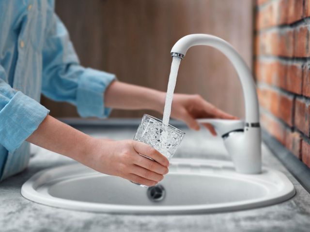 Photo of a person filling water from a faucet